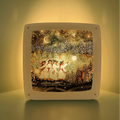 Decorative night light silhoutte with a winter scene of three figures and trees on a white background.